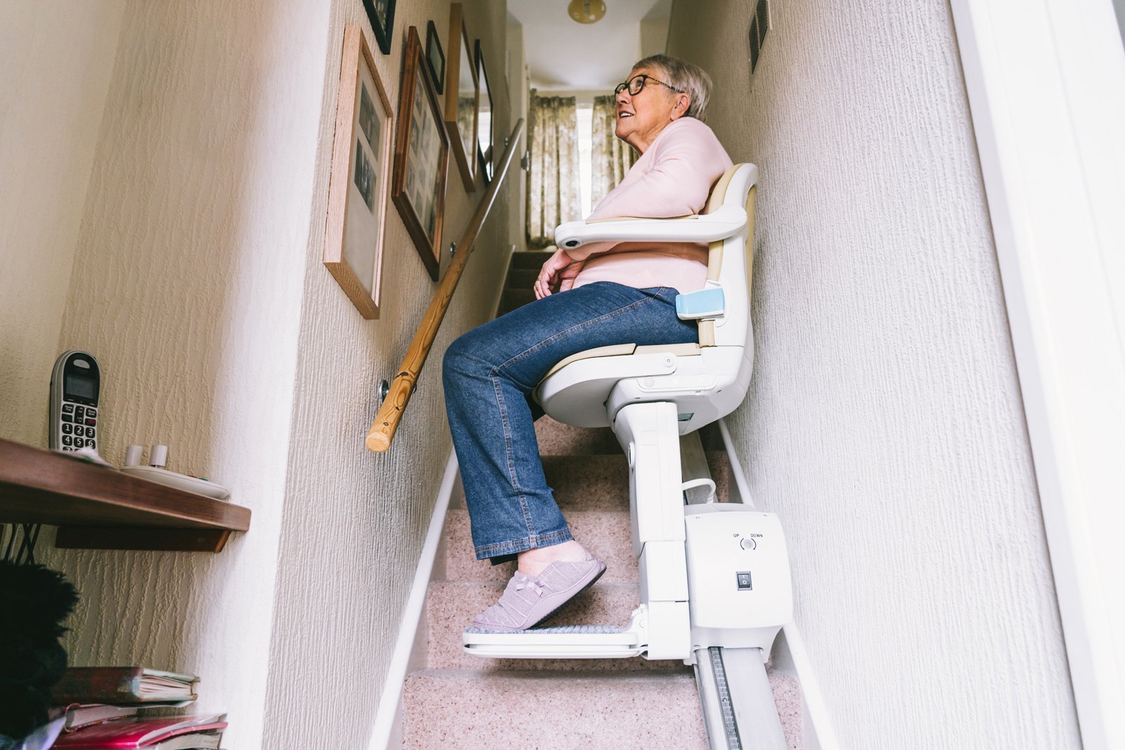 Eine Seniorin sitzt in einem Treppenlift. 