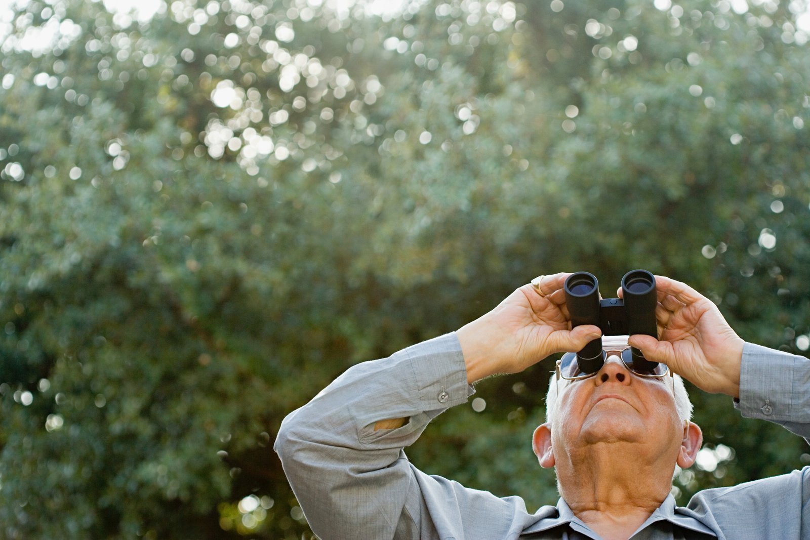 Ein Senior schaut mit dem Fernglas in den Himmel. 