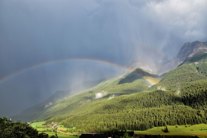 Im Bild ist ein Regenbogen über Scuol zu sehen. 