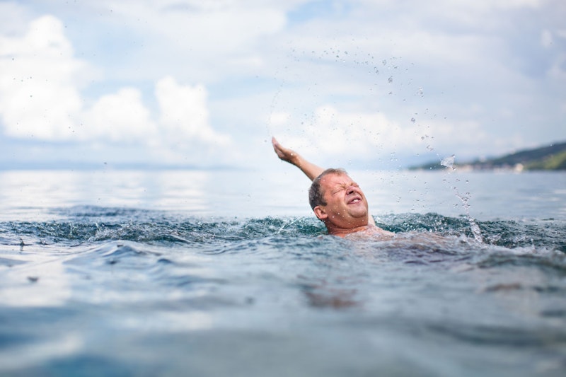 Ein Senior schwimmt im See. 