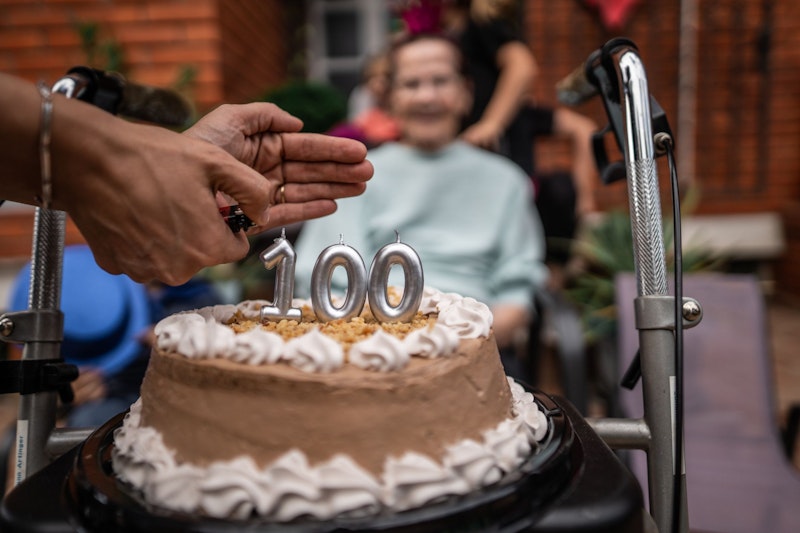 Eine Seniorin im Rollstuhl freut sich über einen Geburtstagskuchen. 